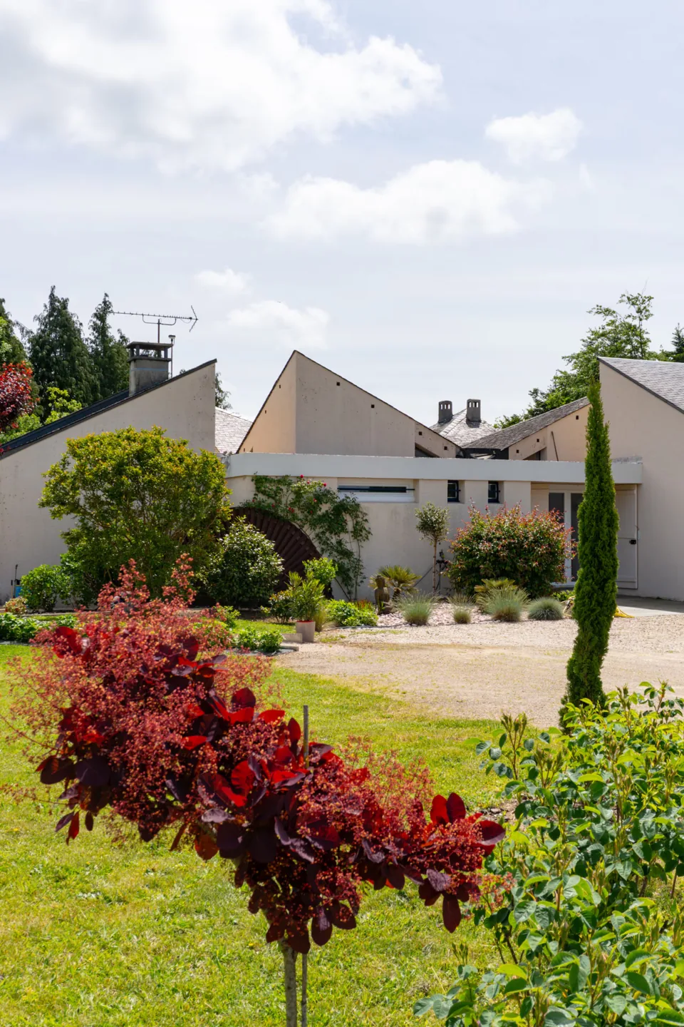 La façade de la maison aux toits géométriques, entourée de plantations